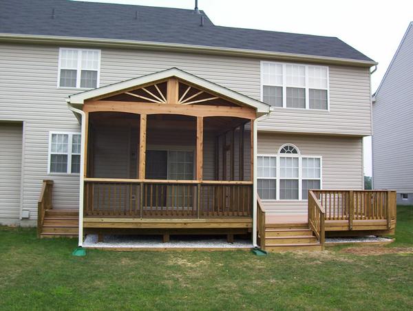 This is a composite deck with wooden balusters and a trex handrail. The screened in porch is wood and there are a set of steps on both sides of the room.